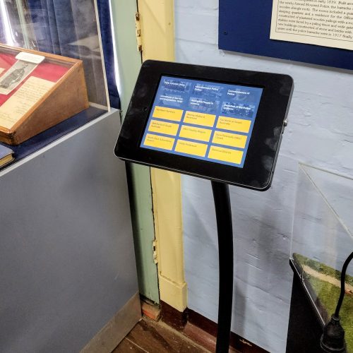 An iPad museum kiosk with 9 large yellow buttons